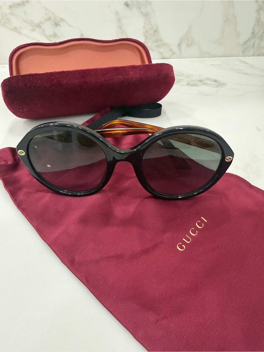 Gucci Womenβs Black Oval Sunglasses with Amber Temples